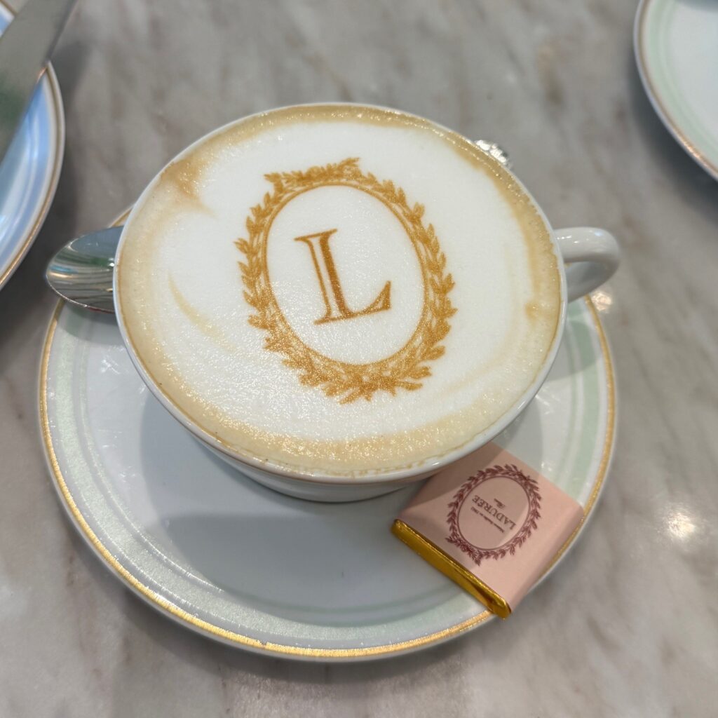 Cappuccino with monogrammed L on the foam served at Ladurée Dubai Hills Mall Royal Afternoon Tea.