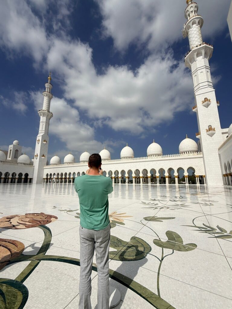 Tourist taking pictures inside the Grand Mosque Abu Dhabi, capturing Islamic architecture and marble details.