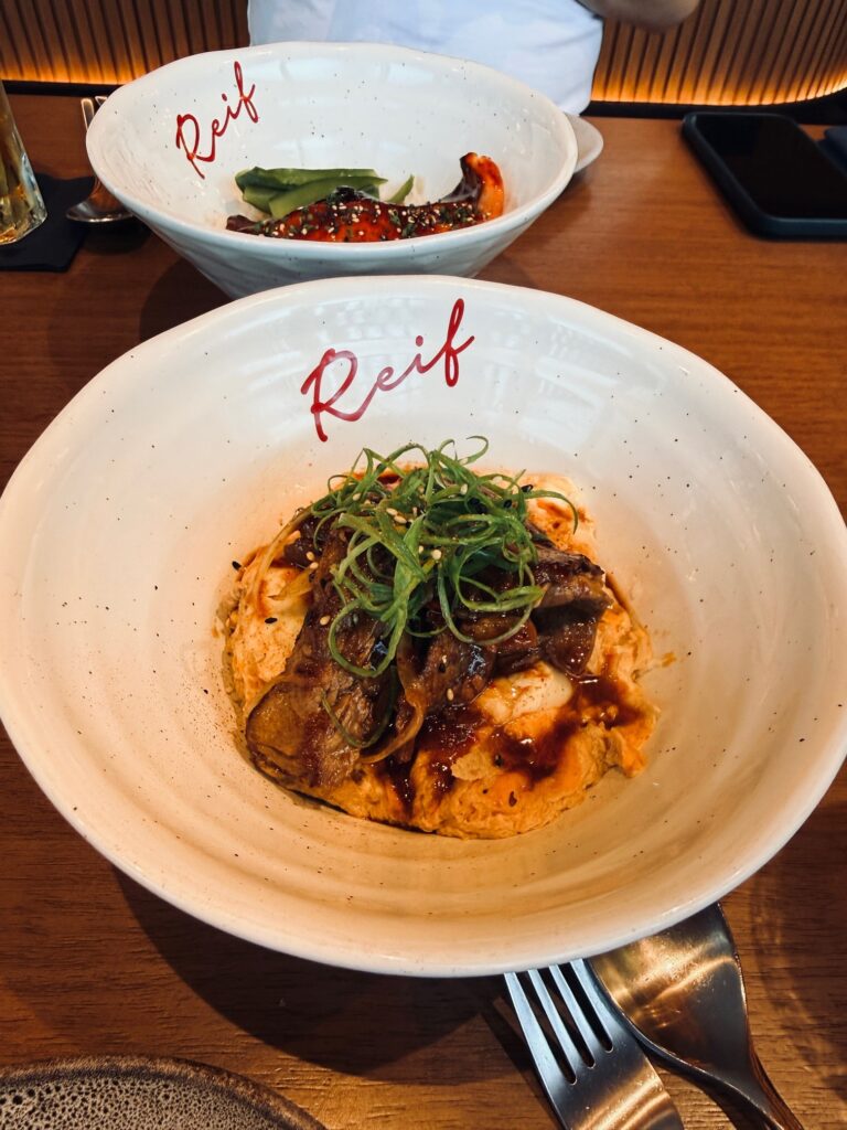 Close-up of gyu toji don at Reif Dubai featuring slow-cooked beef and egg on a bed of rice.