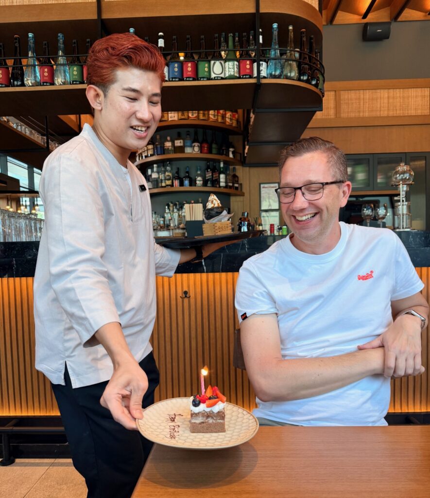 Server presenting a birthday cake to a guest at Reif Japanese Kushiyaki in Dubai.