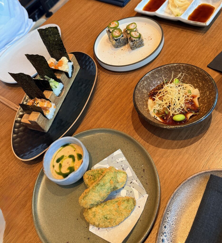 Table shot of four starters at Reif Dubai with chicken gyoza, Chef’s temaki selection, avocado katsu, and hamachi maki.