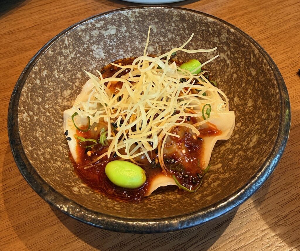 Close-up of chicken gyoza dumplings at Reif Japanese Kushiyaki in Dubai served with spicy sauce.