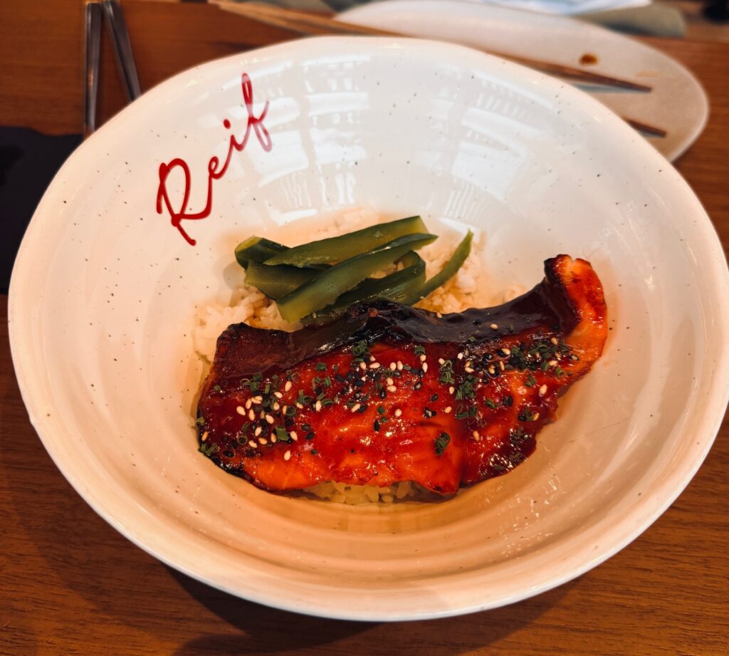 Glazed salmon donburi at Reif Japanese Kushiyaki in Dubai served in a bowl with rice and toppings.